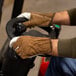 A man wearing Cordova Grain Cowhide leather driver's gloves on a machine.