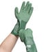 A pair of small green Cordova rubber gloves being worn on a pair of hands.