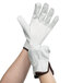 A pair of hands wearing white Cordova cowhide driver's gloves with brown trim.