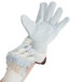 A person wearing small Cordova white canvas warehouse gloves with leather palms and rubber cuffs.