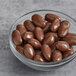 A bowl of Albanese milk chocolate covered almonds on a white surface.