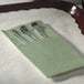 A tray with a Hoffmaster soft sage green dinner napkin with silverware inside.