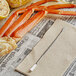 Nantucket Seafood stainless steel seafood fork and spoon next to crab legs on a newspaper.