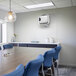 A room with a table and blue chairs with a Fellowes AeraMax Pro air purifier on the wall.
