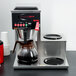 A Grindmaster automatic coffee brewer on a counter with three warmers.