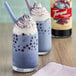 Two glasses of blueberry galaxy bubble tea with whipped cream and toppings made using Torani Puremade Galaxy flavoring syrup.