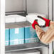 A person in gloves opening a blue box of 10 lb. Dry Ice in a refrigerator.