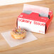 A donut with sprinkles on top of it next to a box of Durable Packaging bakery tissue.