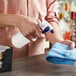 A person using a Lavex blue spray bottle to clean a table with a blue towel.