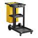 A black Lavex janitor cart with a yellow bag on it.