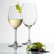 Two Stolzle Classic Chardonnay wine glasses filled with white wine next to a chocolate bar.