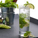 A Stolzle New York tumbler filled with water, limes, and mint leaves.