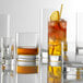 A group of Stolzle New York Collins Glasses with different colored drinks.