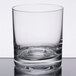A close up of a Stolzle New York Rocks glass with a small amount of liquid in it.