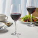 Two Stolzle New York Bordeaux wine glasses on a table with a glass of red wine and salad.