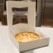 A pie in a 10" x 10" white bakery box with a window on the lid.