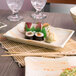 A rectangular melamine plate with sushi on a table.