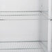 A white Traulsen reach-in refrigerator with metal shelves.