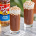 A glass of Torani Salted Caramel Flavoring Syrup in brown liquid with whipped cream on top.