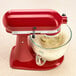 A red KitchenAid stand mixer with a KitchenAid glass bowl of liquid.