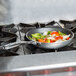A Vollrath Wear-Ever aluminum non-stick fry pan filled with vegetables cooking on a stove.