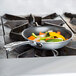 A Vollrath Wear-Ever aluminum non-stick fry pan with vegetables cooking on a stove top.