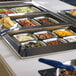 A Vollrath Miramar stainless steel food pan on a buffet table filled with food.