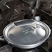 A Vollrath Wear-Ever aluminum non-stick fry pan with a black silicone handle on a stove.