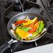 A Vollrath Wear-Ever fry pan filled with peppers and onions cooking on a stove.