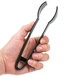 A hand holding a black Fineline 7" plastic tongs.