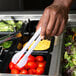 A person using a white Fineline plastic tong to serve themselves at a salad bar.