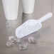 A white plastic Fineline utility scoop with ice on a table.