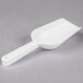 A Fineline white plastic utility and ice scoop on a gray surface.