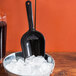 A black Fineline utility scoop in a bowl of ice cubes.