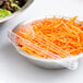 A bowl of salad with shredded carrots served with a clear plastic Fineline tongs.