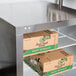 A Traulsen undercounter refrigerator with boxes on a shelf.