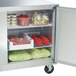 A Traulsen undercounter refrigerator with food inside, including vegetables and meat.