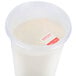 A plastic container with a white substance in it and a red Noble Products Wednesday food labeling sticker.