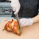 A person using a Mercer Culinary Millennia Colors chef knife to cut a turkey.