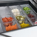 A stainless steel Traulsen sandwich prep table with food in containers on the counter.