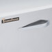 A close up of the left hinged door handle on a stainless steel Traulsen sandwich prep table.