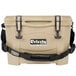 A tan Grizzly Cooler with black handles and straps.