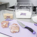A Mercer Culinary Millennia Colors® purple chef knife cutting raw meat on a cutting board.