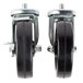 A pair of Traulsen casters with black rubber wheels and metal nuts.