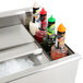 A stainless steel Eagle Group underbar ice bin with bottle holders holding bottles of liquid.