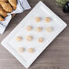 A white 10 Strawberry Street rectangular porcelain platter with pastries and croissants on it.