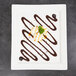 A white rectangular porcelain platter with chocolate drizzled on top of food.
