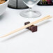 A pair of wooden chopsticks resting in a Town Hourglass T-Line chopstick holder.