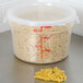 A Cambro translucent round plastic food storage container filled with pasta.