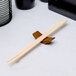 A pair of wooden chopsticks on a Town traditional wood chopstick rest.
